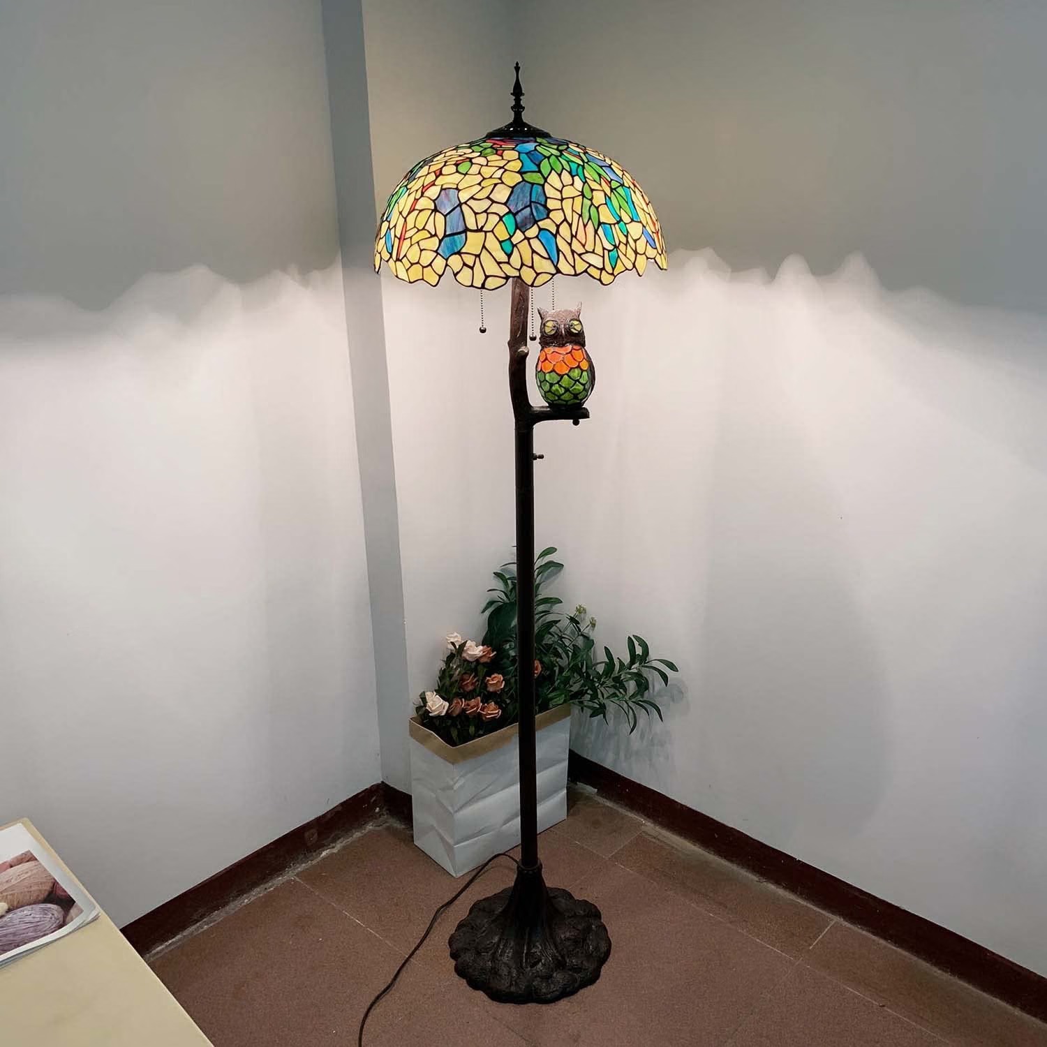 Tiffany-style stained glass floor lamp with a wisteria pattern shade and a perched owl figure on the stem