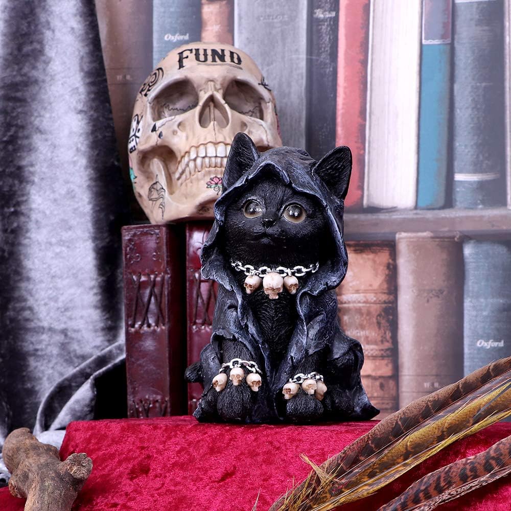 Black cat figurine wearing a hooded reaper cloak with a skull chain necklace and skull-draped paws, seated in front of a skull