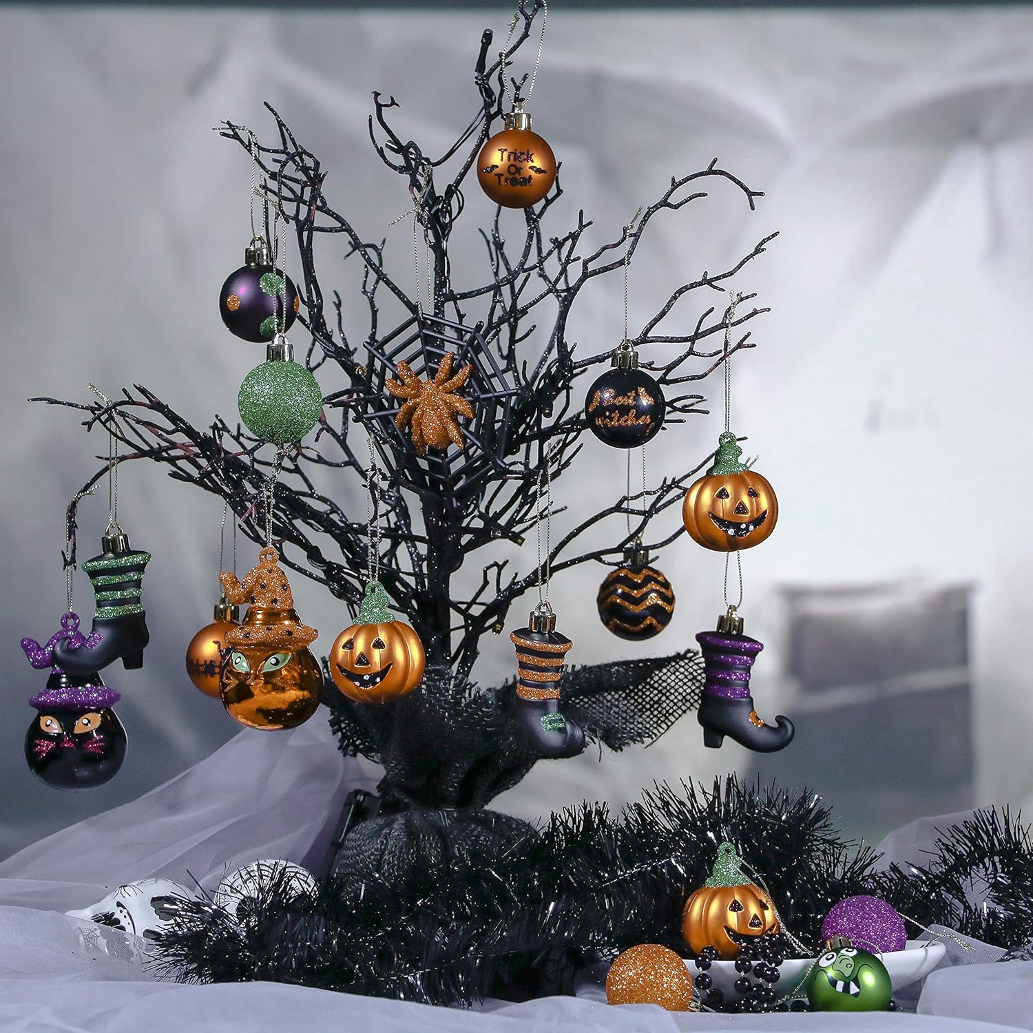 Set of glitter glass Halloween tree ornaments — jack-o'-lanterns, witch hats, witch boots, a spiderweb, and baubles reading Trick or Treat and Bat Witches, in orange, purple, green, and black