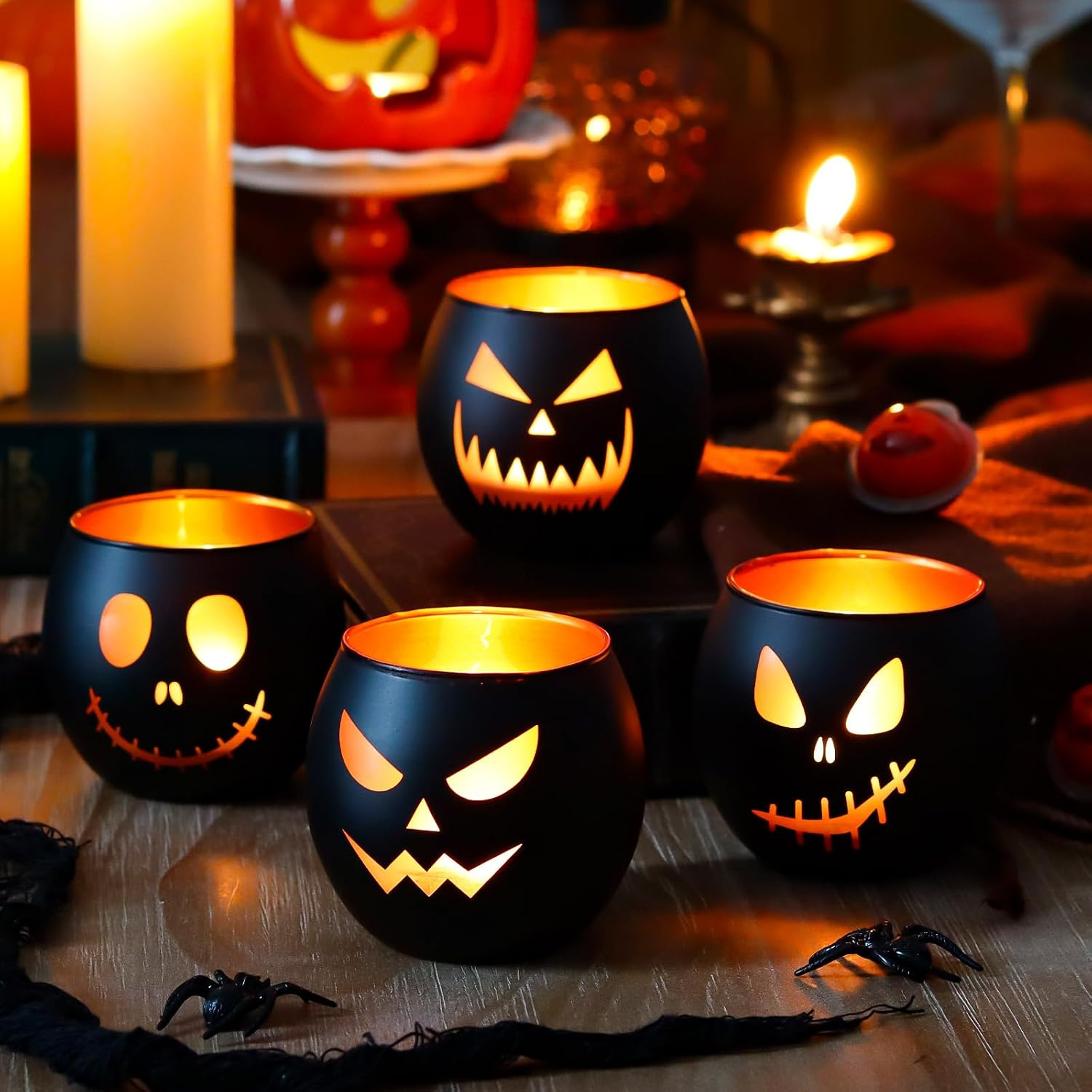Four black glass jack-o'-lantern tealight holders with laser-etched faces and gold interior