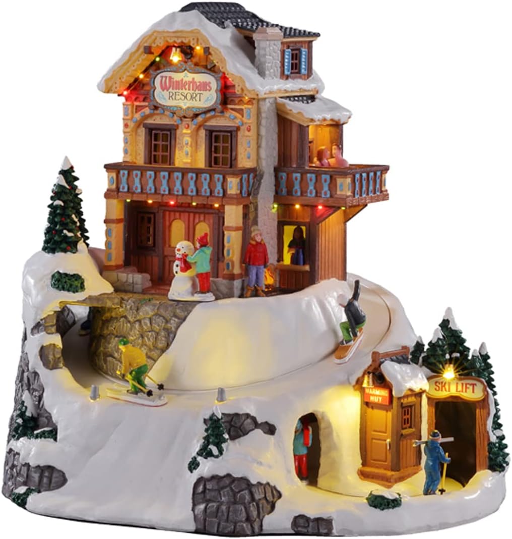 Lemax Winterhaus Resort village piece, an alpine ski lodge with string lights on a snowy mountain, with skiers and a snowboarder on a winding slope, a snowman, a warming hut, and a ski lift entrance