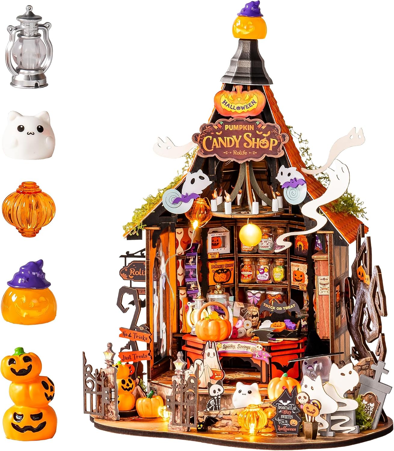 Built Rolife miniature Pumpkin Candy Shop, a witch's-hat-roofed wooden shop lit warm inside, with shelves of tiny candy jars, a pumpkin basket on the counter, little ghosts and cats, a gothic gate, tombstones and No Tricks Just Treats signs