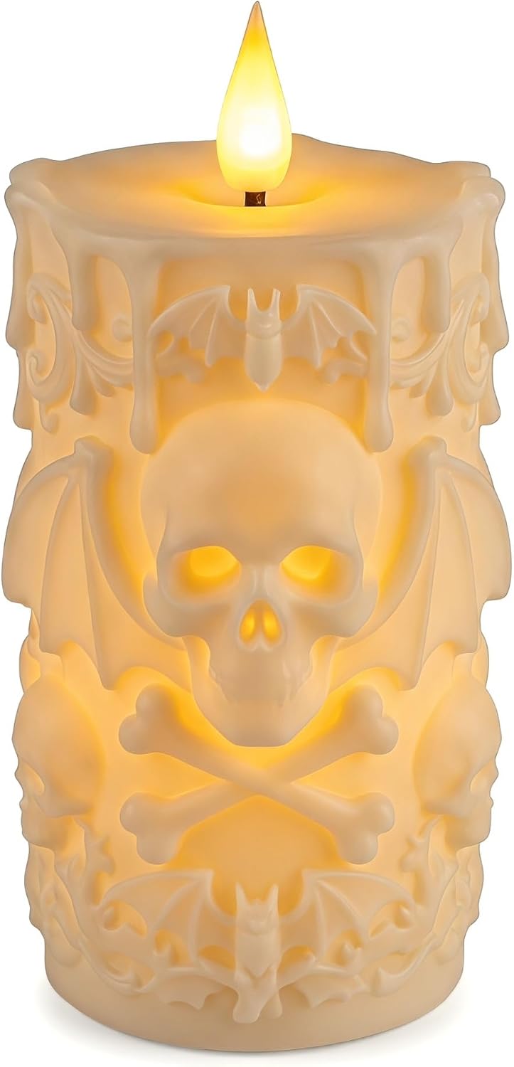 Ivory flameless LED pillar candle carved in relief with a skull and crossbones, bat wings and dripping wax, glowing from within under a flickering flame